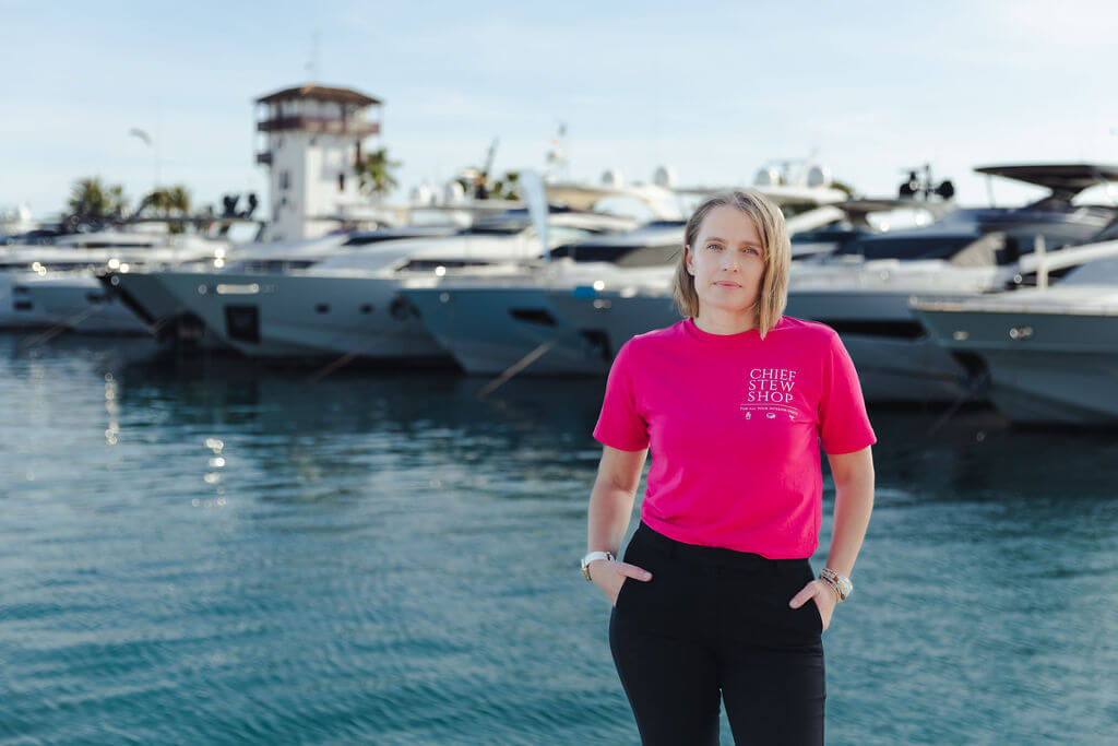 Clair of Chief Stew Shop wearing pink tee shirt and standing in front of yachts at Mallorca marina during her personal branding shoot. 