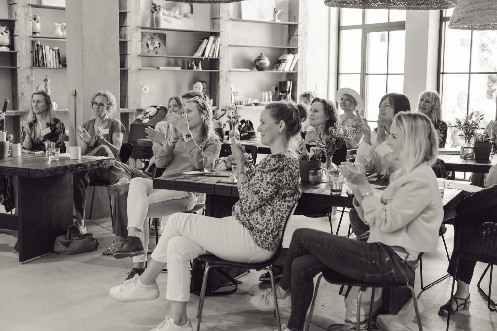 women sitting and clapping hands at networking event