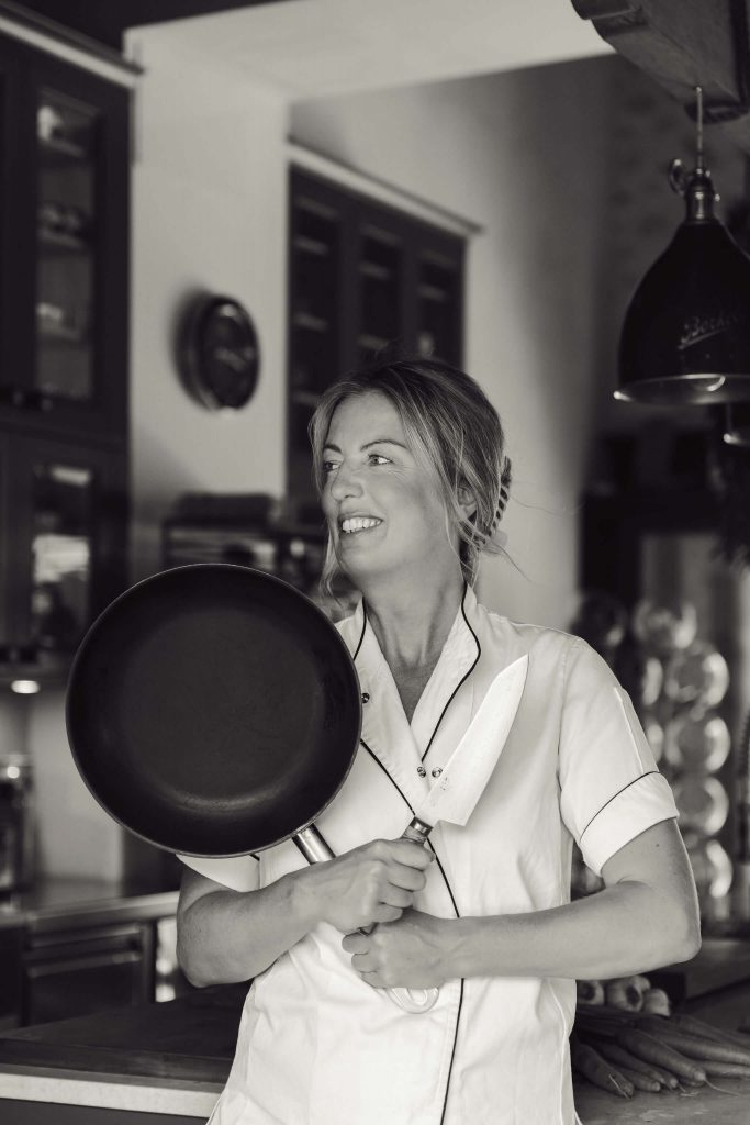 Private chef Ida in kitchen holding pan and knife for personal branding shoot in Mallorca