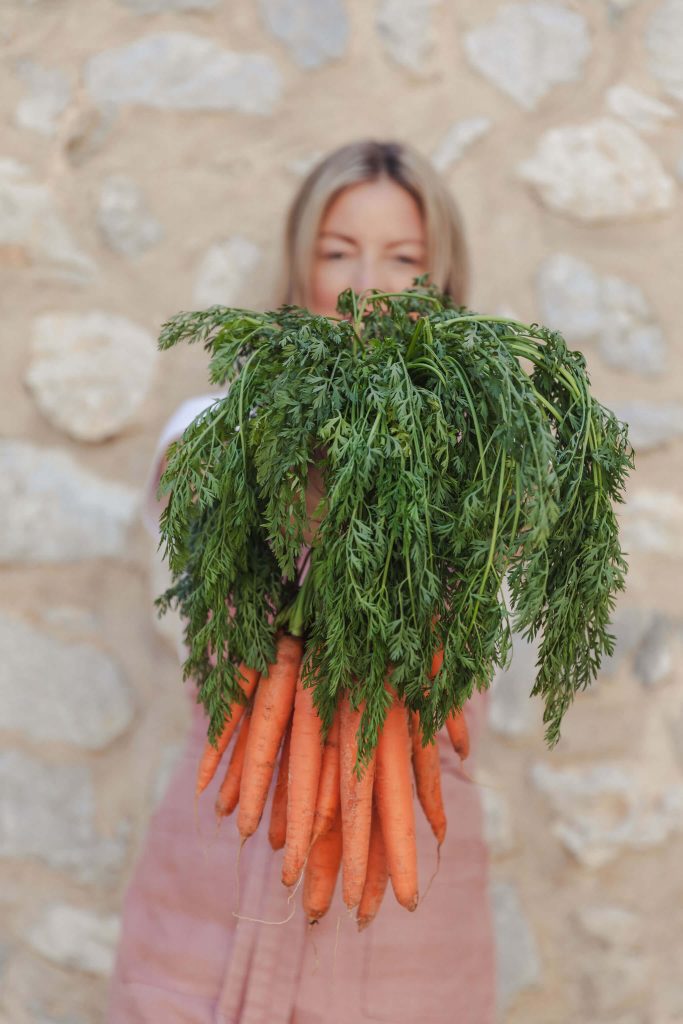 private chef Ida holding carrots for fun portrait for her branding shoot in Mallorca